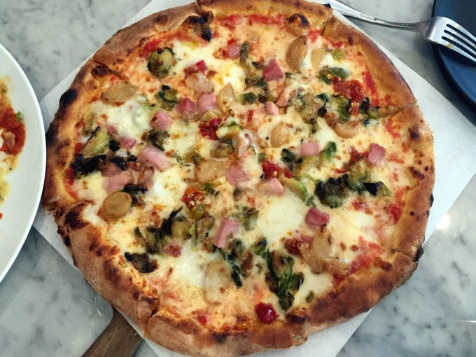Pizza with braised slab bacon, brussels sprouts, roasted garlic, tomato mozzarella, crescent cheese, and calabrian chilies